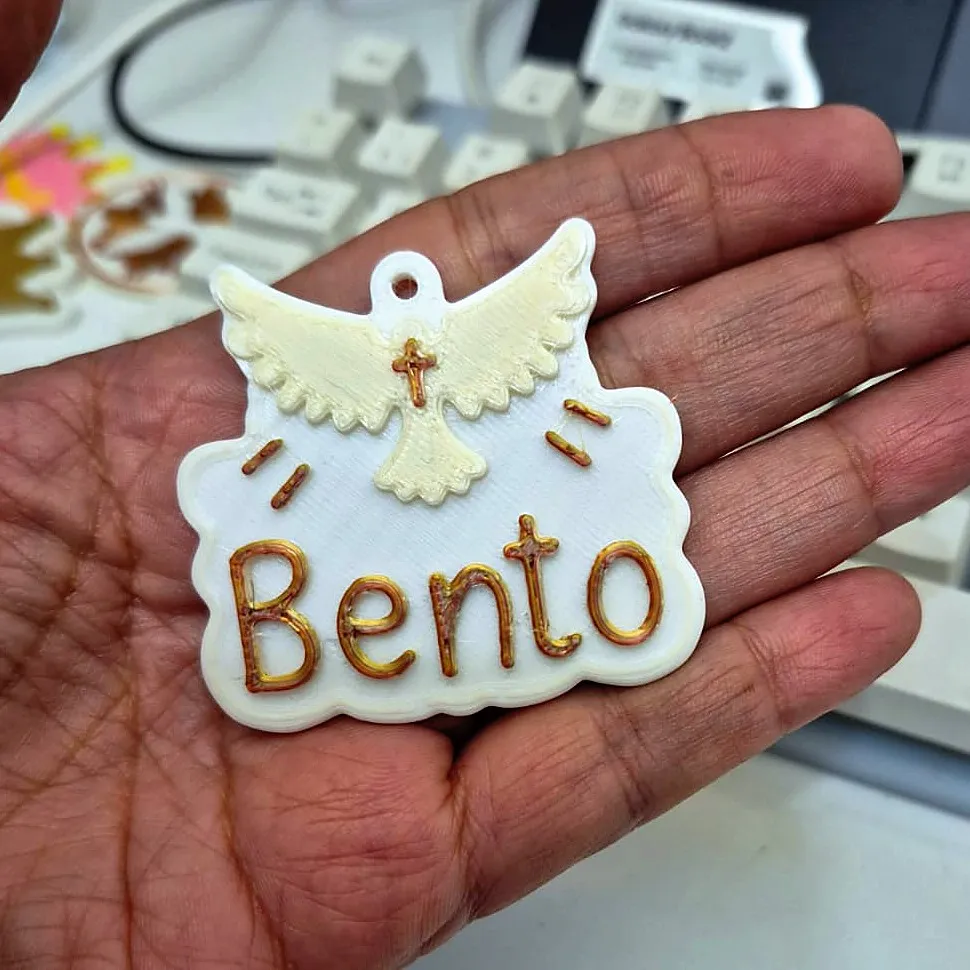 Chaveiro branco com pomba e o nome Bento em dourado, na palma da mão, impresso em 3D pela JC3D