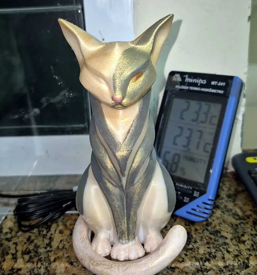 Escultura de gato sentado com faixas geométricas, pintada em dourado e perolado, impressa em 3D pela JC3D
