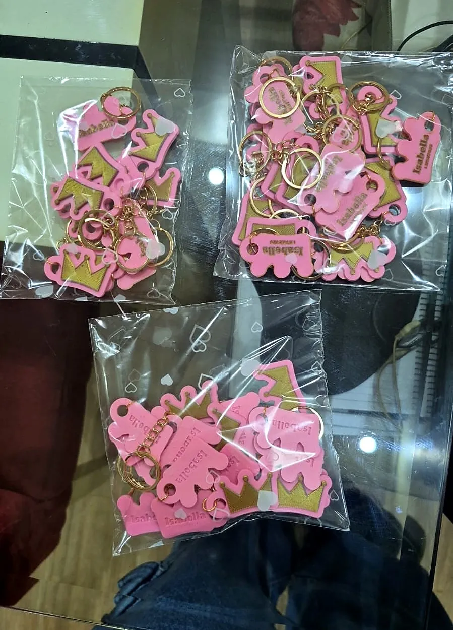 Três saquinhos com chaveiros rosa em formato de coroa dourada, personalizados com nome, embalados para lembrança de festa